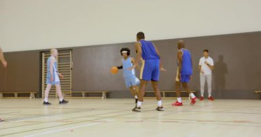 Basketbolcular antrenman sırasında kapalı sahada yoğun bir şekilde yarışıyorlar. Spor, yarışma, takım çalışması, sporcular, antrenman