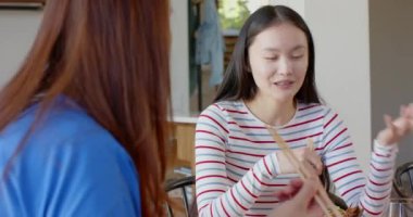 Konuşan ve yemekten zevk alan, çubuklu bir kadın arkadaşıyla sohbet ediyor. Yemek, arkadaşlık, yemek, kahkaha, bağlantı, mutluluk