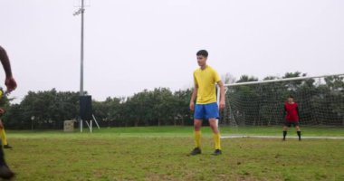 Sahada futbol oynuyor, sarı formalı çocuklar maça odaklanıyor. Spor, takım çalışması, rekabet, gençlik, atletik, açık hava