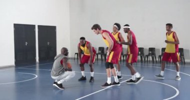 Basketbol takımı sahada koçla toplanıp oyun stratejisine hazırlanıyor. Takım çalışması, spor, sporcular, koçluk, planlama, motivasyon