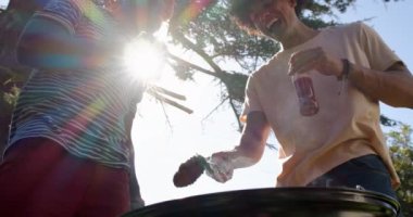 Dışarıda takılmaktan hoşlanan, içki içen ve gün ışığında gülümseyen iki çok ırklı erkek arkadaş. Arkadaşlık, eğlence, açık hava, mutluluk, neşe, içecekler.