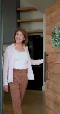Dikey video: Noel kutlaması için arkadaşlara hoşgeldin demek, evde dekorasyonlu neşeli bir kadın. Tatiller, aile, parti, şenlik, toplanma, neşe