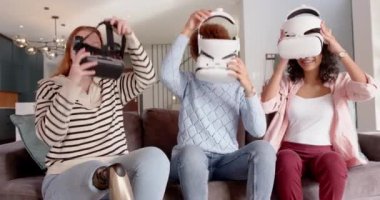 VR kulaklıkları kullanarak, çeşitli bayan arkadaşlar koltukta sanal gerçeklik deneyiminin tadını çıkarıyorlar. Teknoloji, eğlence, eğlence, fütüristik, boş zaman, oyun