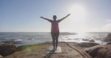 Paspasın üzerinde yoga, güneş doğarken okyanusta meditasyon yapan olgun Asyalı kadın. Meditasyon, sağlık, sükunet, fitness, rahatlama, huzur