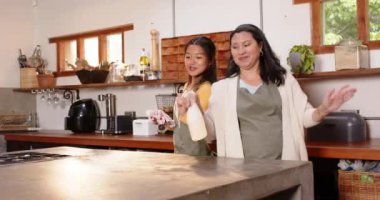 Mutfak tezgahını temizlemek, çok kültürlü genç bir kadın ve büyükannenin evde birlikte gülümsemesi. aile, bağ, çok nesilli, birliktelik, mutluluk, aile içi