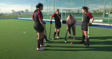 Kadın hokey takımı güneşli antrenman sırasında sahada strateji kuruyor. Takım çalışması, spor, sporcular, strateji, rekabet, kadınlar