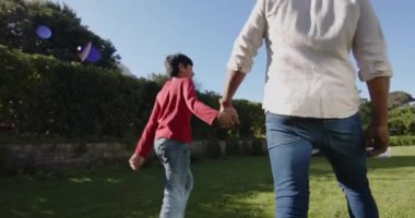 El ele tutuşuyorlar, Hintli baba ve küçük oğlu bahçede birlikte yürüyüp eğleniyorlar. Aile, bağ, birliktelik, ebeveyn, çocuk, doğa