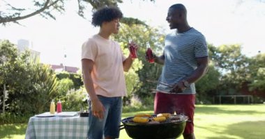 Barbeküde mısır ızgara, iki çok ırklı erkek arkadaş gazoz içiyor ve dışarıda takılmanın tadını çıkarıyor. Arkadaşlar, sosyalleşme, yaz, eğlence, toplanma, yemek