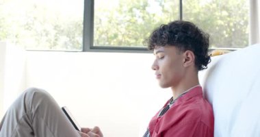 Akıllı telefon tutmak, genç bir çocuğun kanepede oturup evde konuşması. Teknoloji, iletişim, rahatlama, yaşam tarzı, sohbet, kapalı alan