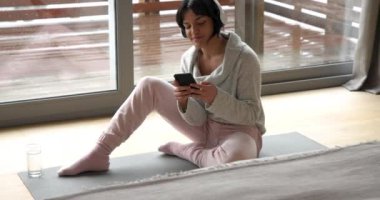 Evde dinlenen, yoga minderinde kulaklıkla meditasyon yapan bir kadın. Meditasyon, farkındalık, rahatlama, dinginlik, teknoloji, refah