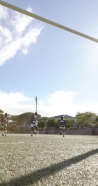 Dikey video: Rugby oyuncuları sahada koşuyor, topu tutuyor, açık havada antrenman yapıyorlar. Spor, takım çalışması, atletizm, açık hava, rekabet, egzersiz