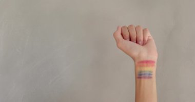 Yumruk kaldıran, bileğinde gökkuşağı bayrağı olan biri. LGBTQ, eşitlik, destek, dayanışma, aktivizm, çeşitlilik