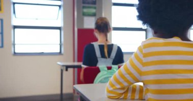 Okulda, sırt çantalı bir kız sınıfın masasında oturuyor, yüzü öne dönük. Eğitim, okula dönüş, öğrenme, öğrenme, çocukluk