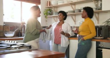 Mutfakta, arkadaşlar birlikte içki içerken gülüp sohbet ediyorlar. Toplanma, sohbet, sosyalleşme, mutluluk, aydınlık, yaşam tarzı