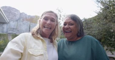 Gülümseyen ve el sallayan, iki çok ırklı son sınıf kız arkadaş dışarıda eğleniyor. Arkadaşlık, mutluluk, rahatlık, yaşlılık, birliktelik, bağ.