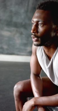 Dikey video: Odaklanmış sporcu spor salonundaki yoğun egzersizden sonra dinleniyor, kararlılık gösteriyor. Fitness, egzersiz, güç, motivasyon, dayanıklılık, eğitim