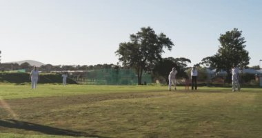 Güneşli bir günde kriket oynamak, sahada beyaz üniformalı kadın oyuncular. Spor, yarışma, takım, sporcular, açık hava, çim