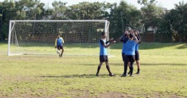 Futbolcular güneşli bir günde kale direğinin yanında saha dışına çıkıyorlar. Sporcular, spor, takım çalışması, zafer, rekabet, oyun