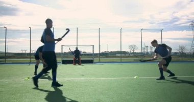 Çim hokeyi oynuyorlar, erkekler dışarıda kaleciyle antrenman yapıyorlar. Spor, atlet, takım çalışması, antrenman, rekabetçi, kaleci