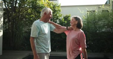 Güneşli bahçede, kıdemli çift kucaklaşıyor ve dışarıda sıcacık gülümsüyor. Yaşlılar, mutluluk, emeklilik, sevgi, neşe, birliktelik