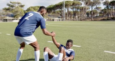 Takım arkadaşının ayakta durmasına, rugby Afrika kökenli Amerikalı erkek oyuncuların sahada, sporda ve fotokopi alanında antrenman yapmasına yardım ediyor. destek, sporcular, güç, işbirliği, fitness