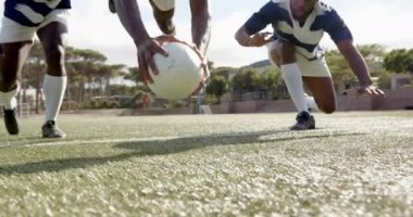 Rugby oynayan Afro-Amerikan adam, maç sırasında çimlerde yatarken topu tutuyor. Spor, rekabet, Afro-Amerikan erkek sporcu, sahada, aksiyon, takım