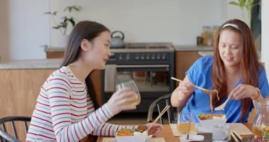 Birlikte öğle yemeği yiyorlar, Asyalı anne ve kızı evde yemek masasında yemeğin tadını çıkarıyorlar. Aile, birliktelik, bağlılık, mutluluk.