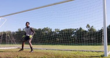 Futbol formalı kaleci kalede duruyor, şutu savunmaya hazır. Spor, atlet, savunma, takım çalışması, rekabet, eğitim