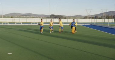 Kadın hokey oyuncuları güneşli açık hava ortamında sahada antrenman yapıyorlar. Spor, takım çalışması, antrenman, egzersiz, açık hava, çim hokeyi