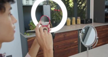 Makyaj yapmak, modern mutfakta ayna ve halka ışığı kullanan biri. Güzellik, kozmetik, kibir, yaşam tarzı, teknoloji, aydınlanma