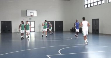 Basketbolcular kapalı sahada yoğun bir şekilde yarışıyor, top sürme becerilerine odaklanıyor. Sporcular, yarışma, spor, takım çalışması, oyun, spor