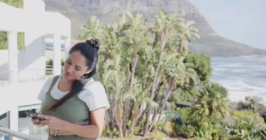 Akıllı telefon tutmak, olgun Asyalı kadın manzaralı kaplıca, balkon, fotokopi odası. Sağlık, rahatlama, doğa, rahatlık, teknoloji, sükunet.