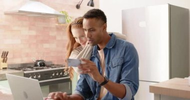 Çevrimiçi alışveriş yapan çeşitli çiftler, mutfak ortamında kredi kartı kullanıyorlar. Çevrimiçi alışveriş, internet, işlem, e-ticaret, yaşam tarzı, finans
