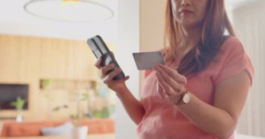 Kredi kartı ve akıllı telefonu elinde tutan, gülümseyen ve online ödeme yapan bir kadın. Alışveriş, ekommerce, digital, işlem, teknoloji, finans