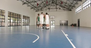 Basketbol takımı spor salonunda toplanıyor, oyun stratejisi tartışmasına hazırlanıyor. Takım çalışması, spor, koçluk, atlet, rekabet, birlik