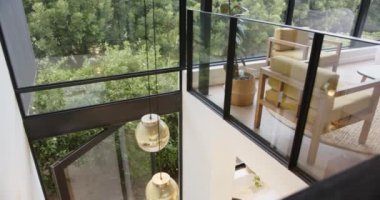 Camdan duvarları olan modern ev odası, rahat oturma alanı, ve dışarısı yemyeşil, kopyalama alanı. Sağlık, rahatlama, lüks, sükunet, iç mekan, rahatlık.