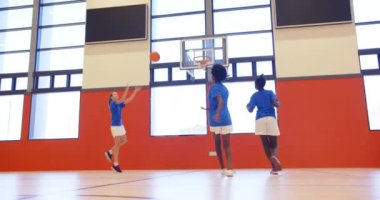 Okulun spor salonunda basketbol oynamak, çocuklar maç sırasında basketbol oynamak. Spor, takım çalışması, rekabet, egzersiz, eğlence, enerji