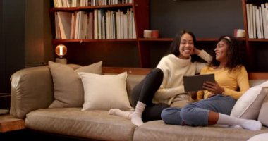 Arkadaşlar kanepede birlikte gülüyor, Şükran Günü 'nde tabletin tadını çıkarıyorlar. Arkadaşlık, kutlama, teknoloji, tatil, birliktelik, eğlence.