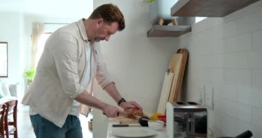 Kıdemli adam modern mutfakta kahvaltıyı ekmek kızartma makinesi ve taze ekmekle hazırlıyor. Yemek pişirme, yaşam tarzı, yemek, ev yapımı, ev yapımı, ev aletleri