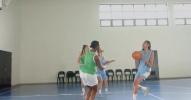 Basketbol oynuyorlar, bayan oyuncular kapalı sahada basketbol seyrediyorlar. Spor, takım çalışması, yarışma, oyun, sporcular, spor salonu