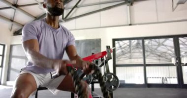 Savaş iplerini kullanarak, Afrikalı Amerikalı adam beden eğitimi için yoğun bir şekilde egzersiz yapıyor. Fitness, egzersiz, egzersiz, dayanıklılık