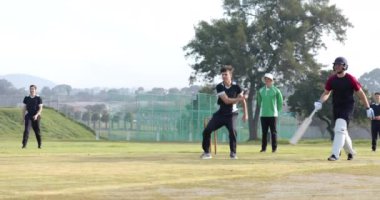 Dışarıda kriket oynuyorlar, güneşli bir günde bir grup erkek maçtan zevk alıyor. Spor, eğlence, takım çalışması, rekabet, aktivite, erkek