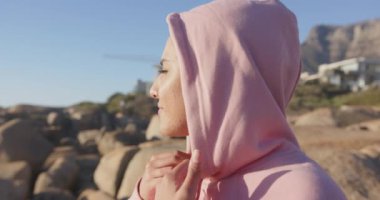 Pembe kapüşonlu, Asyalı bir kadın açık hava manzarasından hoşlanıyor, gözleri güneşten koruyor, fotokopi çekiyor. Açık hava, boş zaman, güneş ışığı, moda, doğa, gündelik