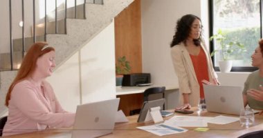 İş konuşmaları, modern ofis ortamında dizüstü bilgisayar ve belge kullanan iki kadın. İş, takım çalışması, işbirliği, iş birliği, teknoloji, toplantı