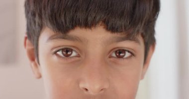 Genç bir çocuğun kameraya ciddi bir ifadeyle baktığı yakın çekim. Çocukluk, portre, duygular, yüz