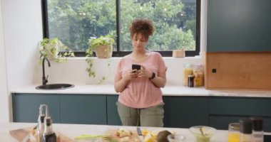Akıllı telefon kullanmak, artı modern mutfakta sağlıklı yemek hazırlayan boyda bir kadın. Yemek pişirme, sağlıklı beslenme, yemek hazırlama, yaşam tarzı, ev, teknoloji
