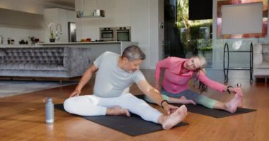 Yoga minderlerine uzanan, çok ırklı üst düzey çiftler evde yoga egzersizleri yapıyorlar. Sağlık, fitness, meditasyon, kapalı alan, yaşam tarzı, rahatlama