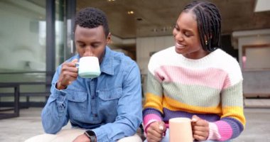 Evde elinde kahve fincanı tutarak adamı besleyen bir kadın. Afro-Amerikan çift, kaynaşma, kahvaltı, sabah, şefkat, birliktelik