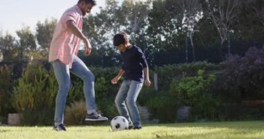 Arka bahçede futbol oynarken, Hintli baba ve oğlu birlikte iyi vakit geçiriyorlar. Aile, bağ, eğlence, açık hava, futbol, spor