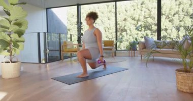 Evde egzersiz yapıyor, ayrıca yoga minderine atlarken halterleri kaldırıyor. Spor, spor, spor salonu, dayanıklılık eğitimi, hamleler, sağlık